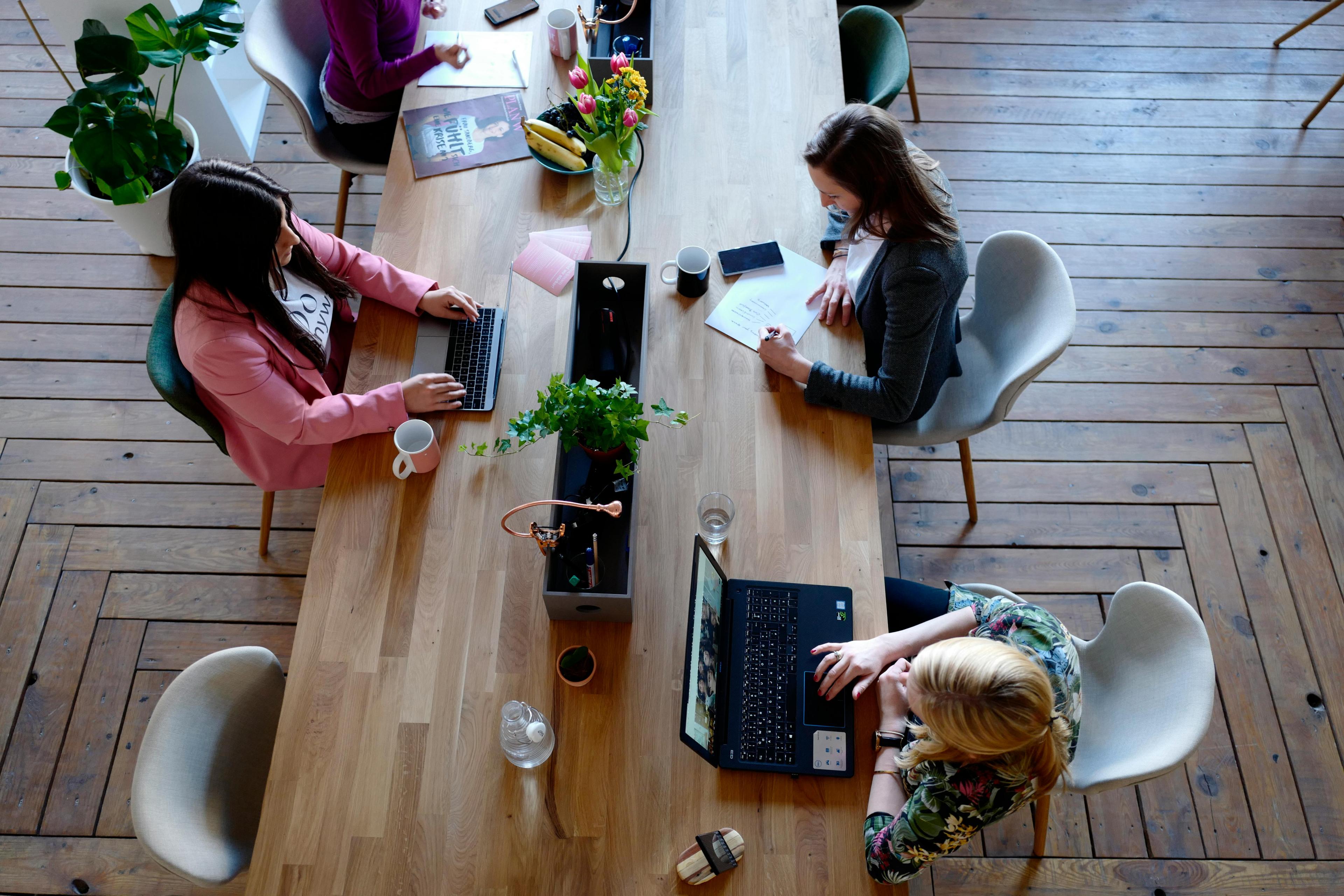 Professional women collaborating around a table with laptops and documents